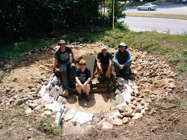 Volunteers create drainage bowl on church lot to capture water off parking lot used to water surrounding perennials