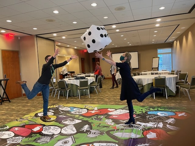 Two people stand on life-sized board game