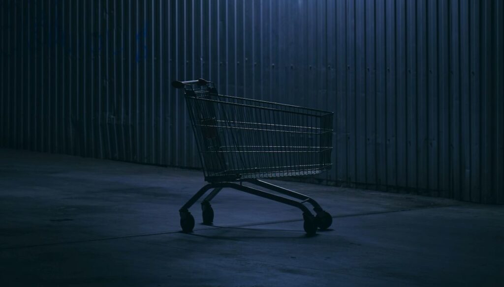 empty shopping cart against corrugated wall in the dark under a spotlight