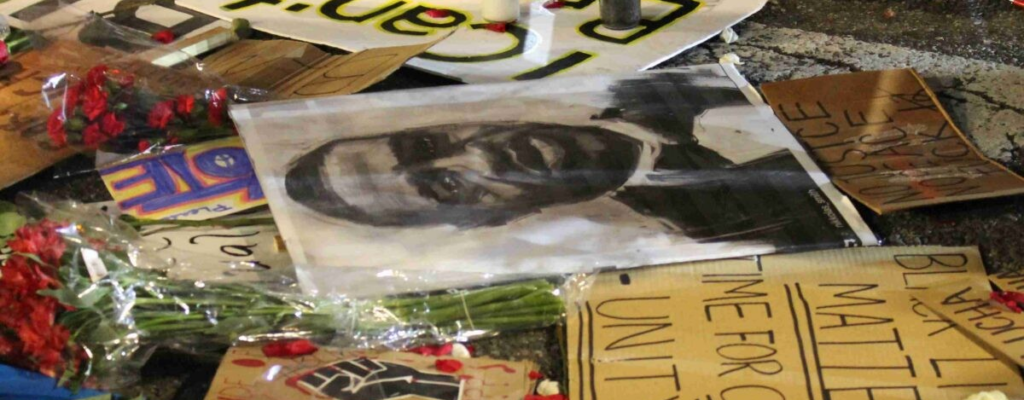 picture showing a memorial for George Floyd with pictures, handmade posters, flowers, etc.
