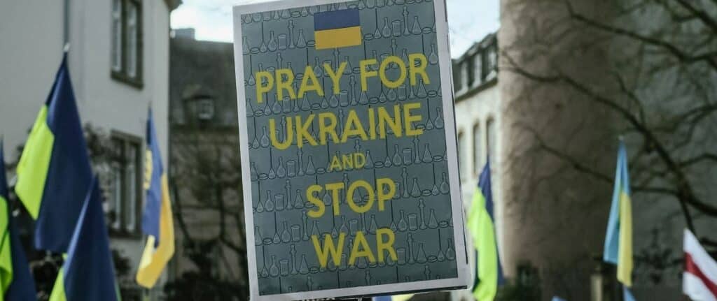 Protester holding a picket sign reading Pray for Ukraine and Stop War